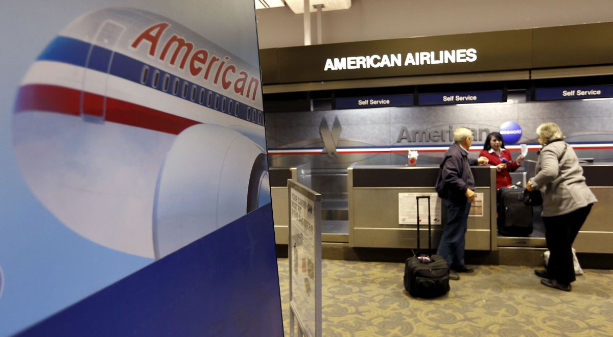 Travelers stand at the American Airlines ticket counter Thursday at Sky Harbor International Airport in Phoenix. American Airlines and US Airways’ merger will create a mega airline with more passengers than any other in the world. (Associated Press)