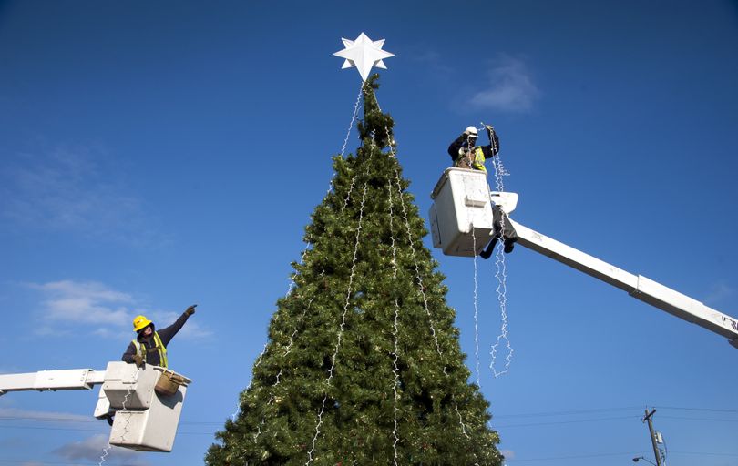 Avista line servicemen Steve Palmer, left, and Clayton Reynolds use their buckets to string up 3,000 lights some 30 feet in the air on the Rotary Club of Spokane Valley’s Christmas tree Tuesday at University City. (Dan Pelle)