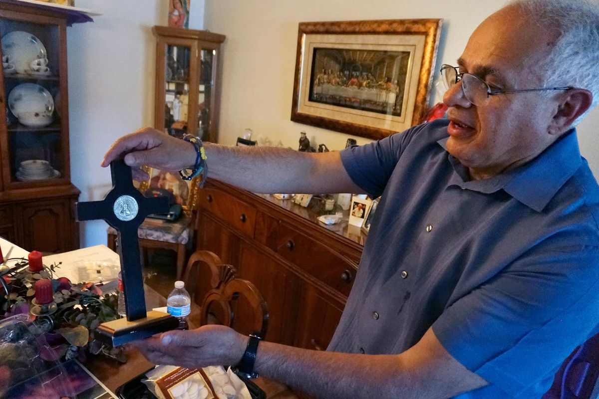 Bob Guerra, a Catholic deacon, holds a crucifix he got to commemorate the visit of Pope Francis to the U.S.-Mexican border at his house in El Paso, Texas, on Sunday, April 3, 2022. Guerra takes the crucifix alongside other liturgical items to help clergy celebrate Mass for hundreds of teens held at a shelter on the Army
