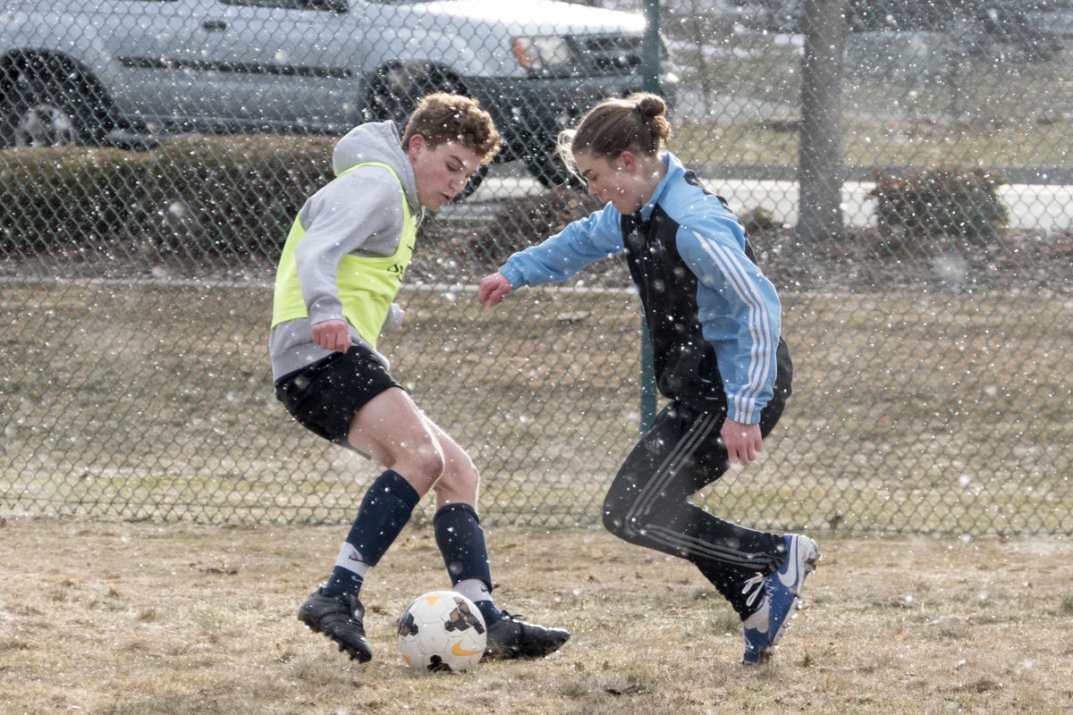 Central Valley High School soccer players Jake Levine, left, and Conner Wold, right, practice in a brief snow shower Monday, March 6, 2017. (Jesse Tinsley / The Spokesman-Review)
