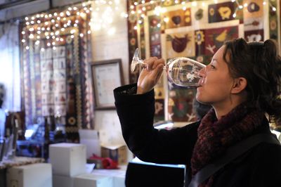 Ariane Smith finishes a taste of wine Saturday at Robert Karl Cellars, one of the wineries open for tastings in Spokane  for the Holiday Wine Fest. The winery had quilts on display, a jewelry artisan and complimentary Moroccan stew for visitors. Fourteen wineries are participating in the festival, which continues today. (Photos by Jesse Tinsley / The Spokesman-Review)