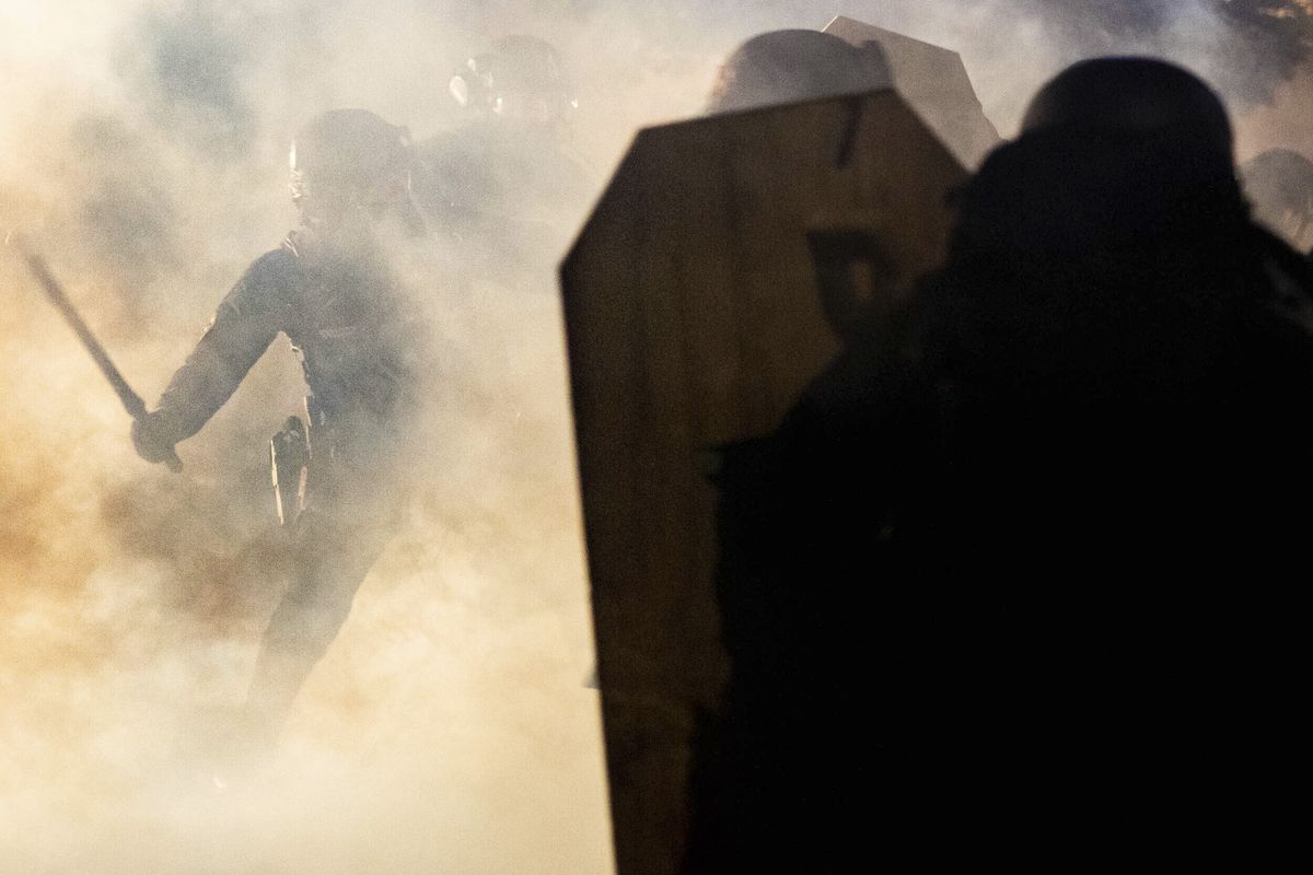 In this Aug. 16, 2020 photo, a Portland police officer wields a club against a protester amidst a cloud of teargas outside of the Penumbra Kelly building in Northeast Portland, Ore. Most police officers who violate citizens’ rights get away with it because the law is heavily stacked in their favor, legal experts say.  (Maranie Rae Staab)