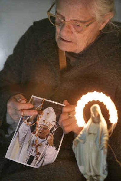 
Concetta Mammalella, 85, prays with a rosary and a photo of Pope John Paul II in a chapel Friday in Naples' Quartieri Spagnoli district in southern Italy.
 (Associated Press / The Spokesman-Review)
