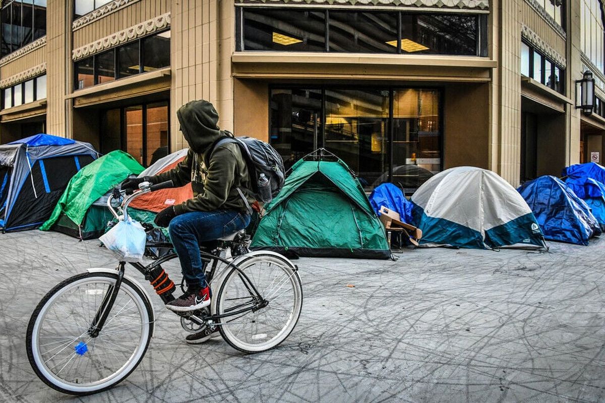 A cyclist takes pause in front of the tent city outside Spokane City Hall in this photo from December 2021.  (DAN PELLE/THE SPOKESMAN-REVIEW)