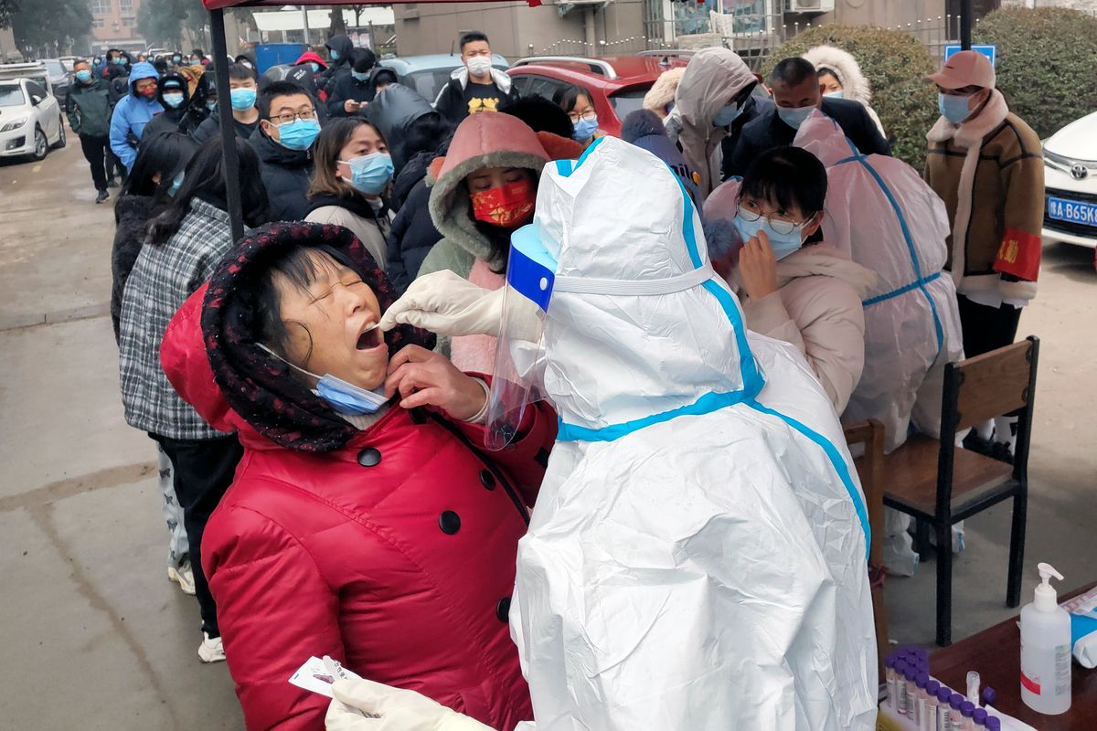 A medical worker wearing a protective suit takes swab samples for the COVID-19 test on residents in Huaxian county in central China