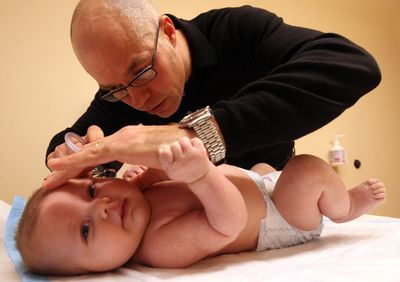 Dr. Chip Roser looks for signs of an infection in the ears of 2 1/2-month-old Loralai Schmidt at his office in Boise. McClatchy (McClatchy / The Spokesman-Review)