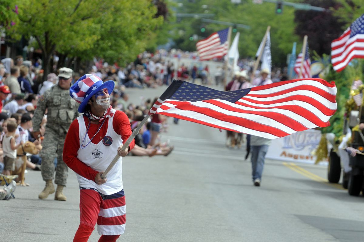 Mickey Metcalf, of Coeur d’Alene, waves an American flag as he dances along Sherman Avenue in downtown Coeur d’Alene  during the American Heroes Parade. Sunday was Metcalf’s birthday. (J. BART RAYNIAK)