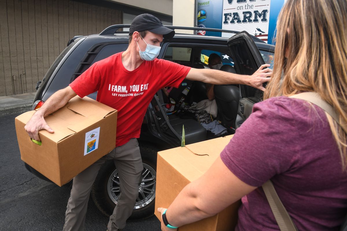 Kyle Jones of Vets on the Farm and Kelsie Higgins of STCU donate their time to deliver food boxes for the Inland Northwest Farmers Market Association to people driving in cars Tuesday, Sept. 15, 2020, at Fairwood Farmers Market. (DAN PELLE/THE SPOKESMAN-REVIEW)
