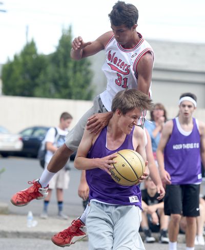 Tyler Thurman leaps over Robbie Bernovich during a game at Hoopfest 2016 in Spokane. (Jesse Tinsley / The Spokesman-Review)