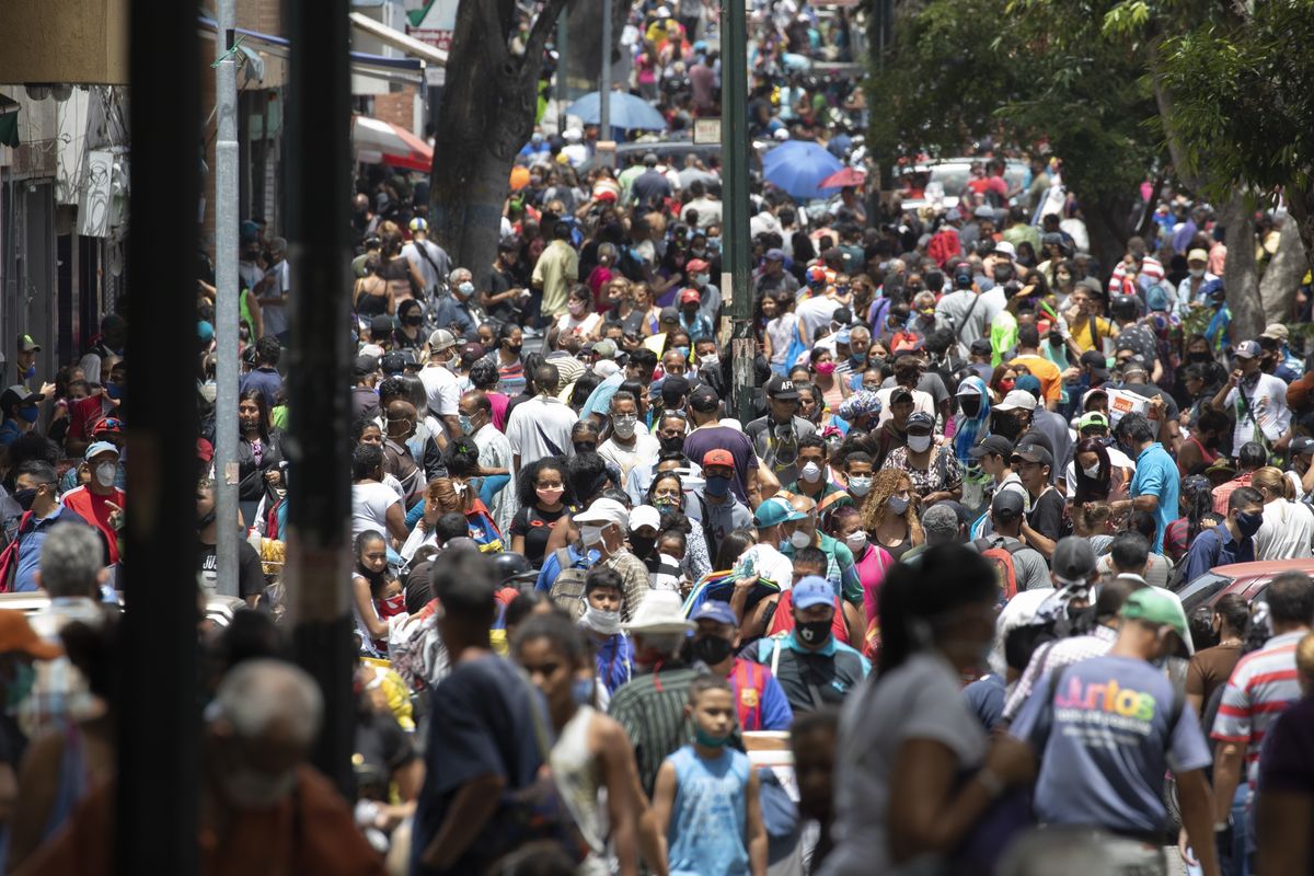 People, some wearing face masks as a measure to curb the spread of the new coronavirus, walk in the Catia neighborhood of Caracas, Venezuela, Saturday, June 20, 2020, during a relaxation of restrictive measures amid the new coronavirus pandemic.  (Ariana Cubillos)
