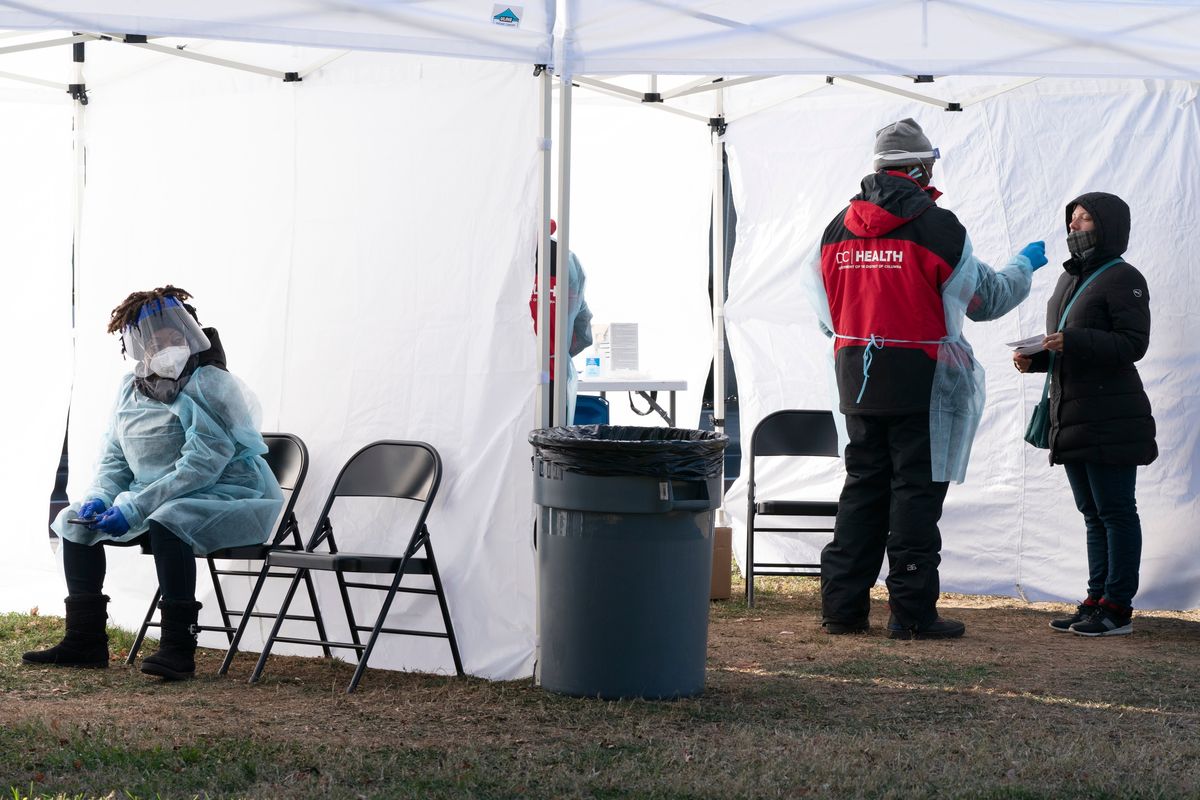 A worker, left, rests for a second between patients, as another person, right, is tested for COVID-19 at a walk-up testing site at Farragut Square on Thursday, just blocks from the White House in Washington, D.C.  (Jacquelyn Martin/Associated Press)