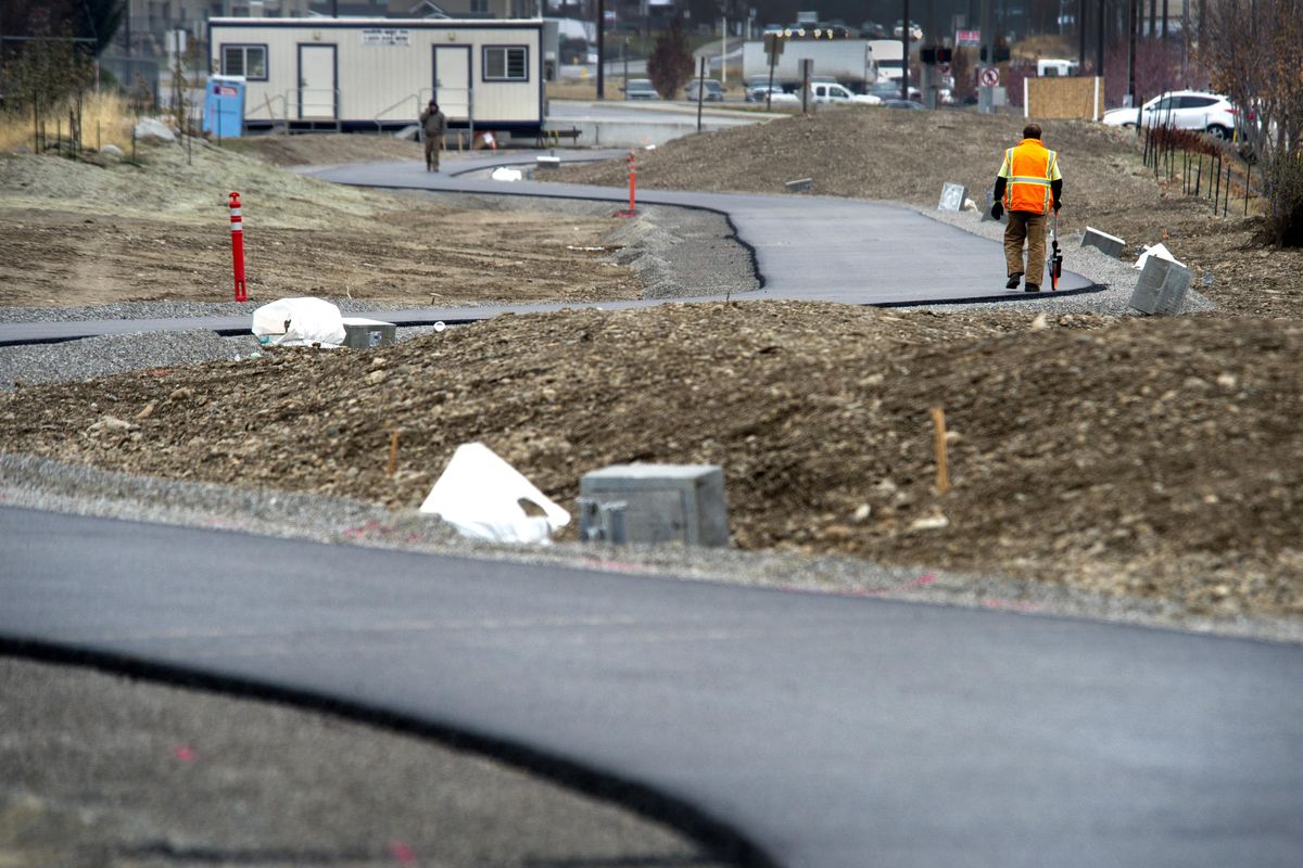 A worker uses a wheel to measure distance for electric cable to supply lighting along the Appleway Trail, Nov.18, 2014, near University Road. (Dan Pelle / The Spokesman-Review)