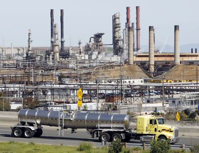 A tanker truck drives by the Chevron oil refinery in Richmond, Calif., on Tuesday. Chevron Corp. says it will cut 2,000 jobs this year and will continue reducing its work force through 2011. (Associated Press)