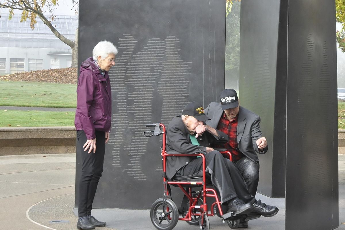 Sidney Walton, of San Diego, a 99-year-old World War II veteran, visits the state’s WWII memorial with his son, Paul, and daughter, Judy, on Wednesday. The memorial has the names of Washingtonians killed in WWII etched on bronze blades that  form shapes representing soldiers and sailors.. (Jim Camden / The Spokesman-Review)