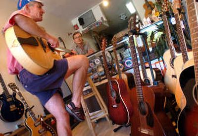 
Jim McKay tries out a guitar at Cole Music Co. in Spokane's Garland district while store owner Eben Cole  describes his selection of new  instruments July 11.  Cole opened his business nearly a year ago and is excited about the future in the Garland neighborhood. 
 (INGRID BARRENTINE / The Spokesman-Review)