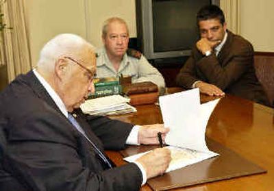 
In this government photo, Prime Minister Ariel Sharon signs an order requiring some 9,000 settlers to leave their homes in the Gaza Strip and four West Bank settlements by July 20 this year at his Jerusalem office Sunday. 
 (Associated Press / The Spokesman-Review)