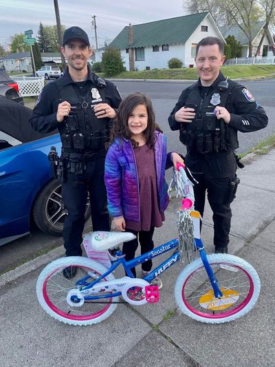 Spokane police officers stand with Stella, 7, and her new bicycle the officers purchased for her after hers was reportedly stolen.  (Courtesy of Spokane Police Department)