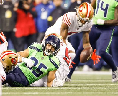 Seattle Seahawks running back Travis Homer (25) fumbles the ball and San Francisco cornerback Charvarius Ward, top, is there to scoop up the second-quarter miscue at Lumen Field on Thursday, Dec.15, 2022, in Seattle. The 49ers won, 21-13.   (Seattle Times)