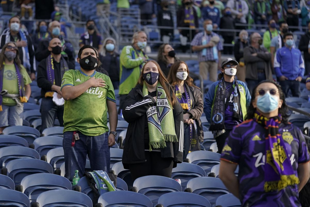 Seattle Sounders fans wear masks as they stand during the singing of the national anthem May 2, 2021, before an MLS soccer match against the Los Angeles Galaxy, in Seattle. Due to a surge in COVID-19 cases King County, which includes Seattle, is reinstating outdoor mask mandates for large events and strongly encouraging people to wear masks in other outdoor settings when they can