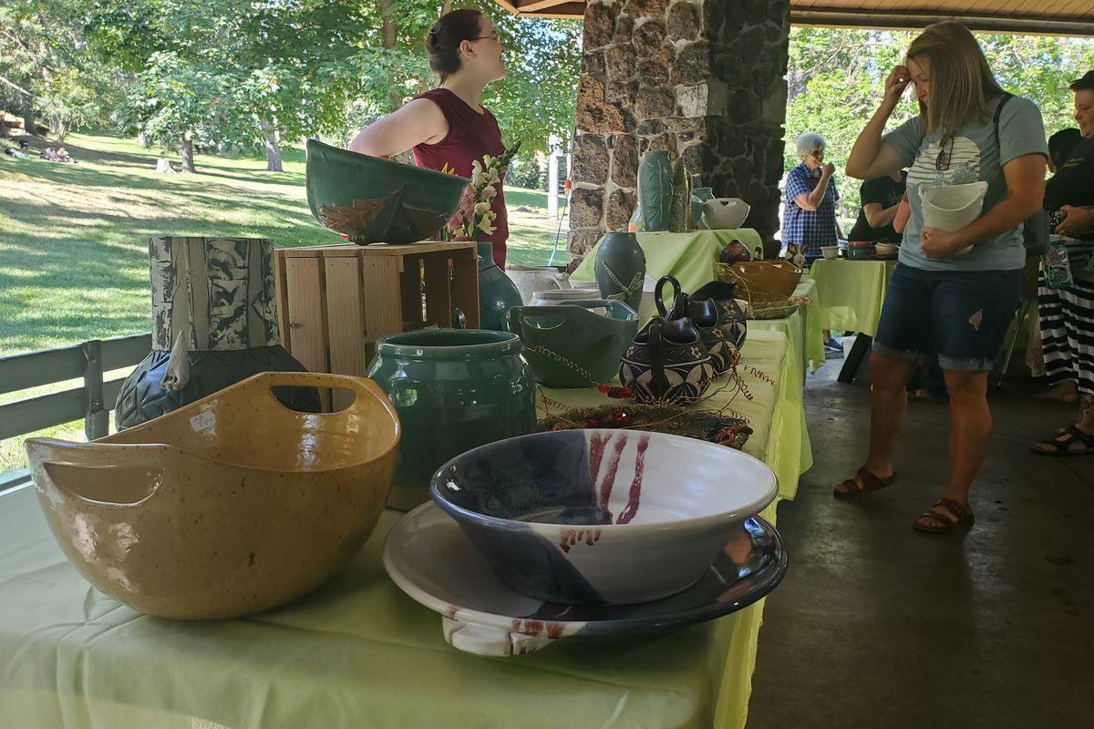 Co-founder of the Urban Art Co-op Karen Mannino presents some of the pottery from artists who premade ceramic bowls for the Scoops and Bowls event at Manito Park on Saturday. (Sydney Brown/The Spokesman-Review)