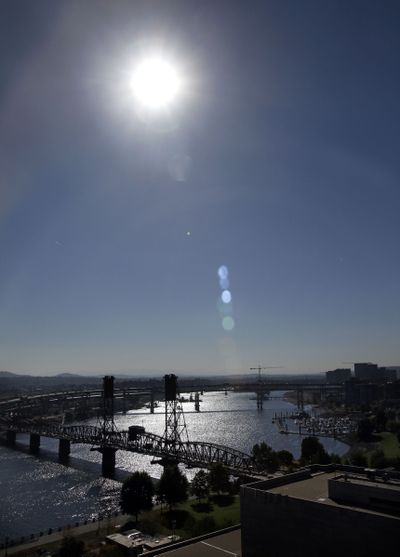 The sun reflects off the Willamette River as its waters pass under the Hawthorne Bridge in downtown Portland on Thursday. (Associated Press)