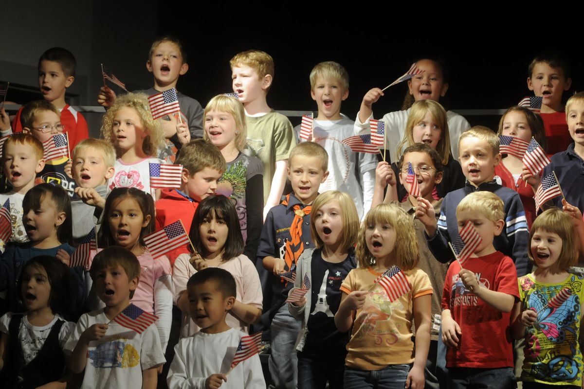 The Adams Elementary School kindergarten and first-grade chorus wave American flags while singing “I am Free” during the Veterans Day celebration Nov. 10. (J. BART RAYNIAK)