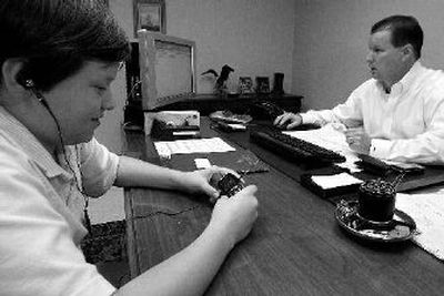 
Brian Durham, 12, watches a show on his cell phone while his father, Charles Durham, works in his office in Jacksonville, Fla. 
 (Associated Press photos / The Spokesman-Review)