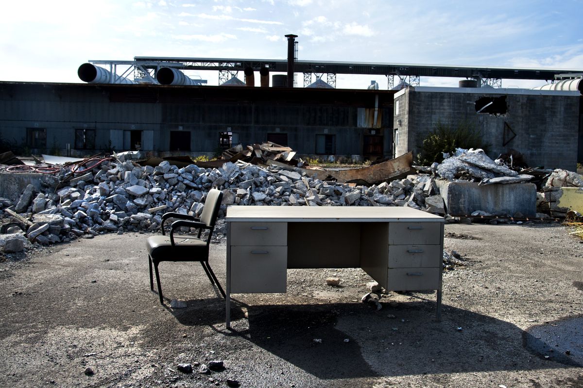 A lone desk and chair await truck drivers doing paper work while scrap metal is loaded onto their rigs at the old Kaiser Mead smelter in this September 2013 photo. The site, originally slated for demolition and redevelopment, remains abandoned and is contaminating groundwater north of town, according to the EPA.   (DAN PELLE)