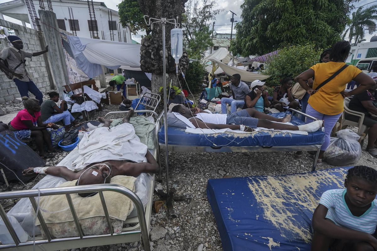 Injured people lie in beds outside the Immaculée Conception hospital in Les Cayes, Haiti, Monday, Aug. 16, 2021, two days after a 7.2-magnitude earthquake struck the southwestern part of the country.  (Fernando Llano)