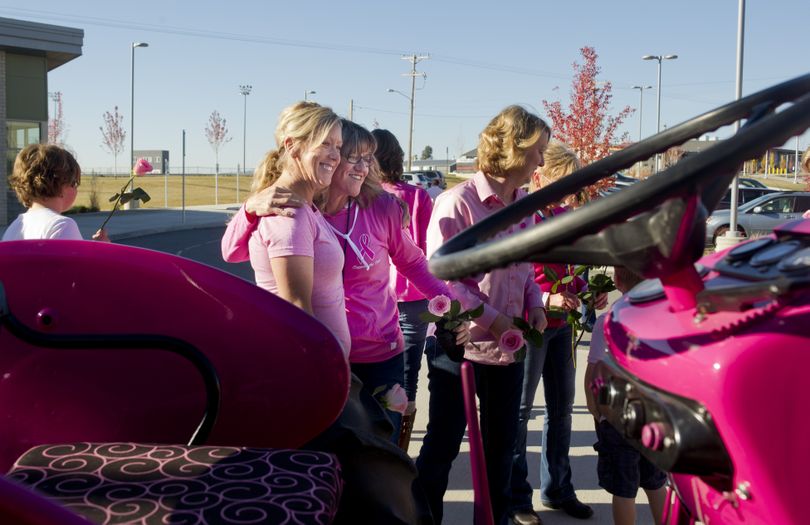 Leslie Malloy and cancer survivor Barb Gady, staff members at Freeman Elementary, hug after posing for a group photo with other Freeman employees in front of a pink tractor from Northwest Farm Credit Services. (Tyler Tjomsland)