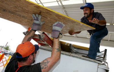 
Joe Munoz, top, grabs a piece of wood from the roof of his van from A.J. Mancabelli at a Home Depot store in McAllen, Texas, on Tuesday. Residents lined up in front of the store to purchase wood to protect their homes from Hurricane Emily. 
 (Associated Press / The Spokesman-Review)