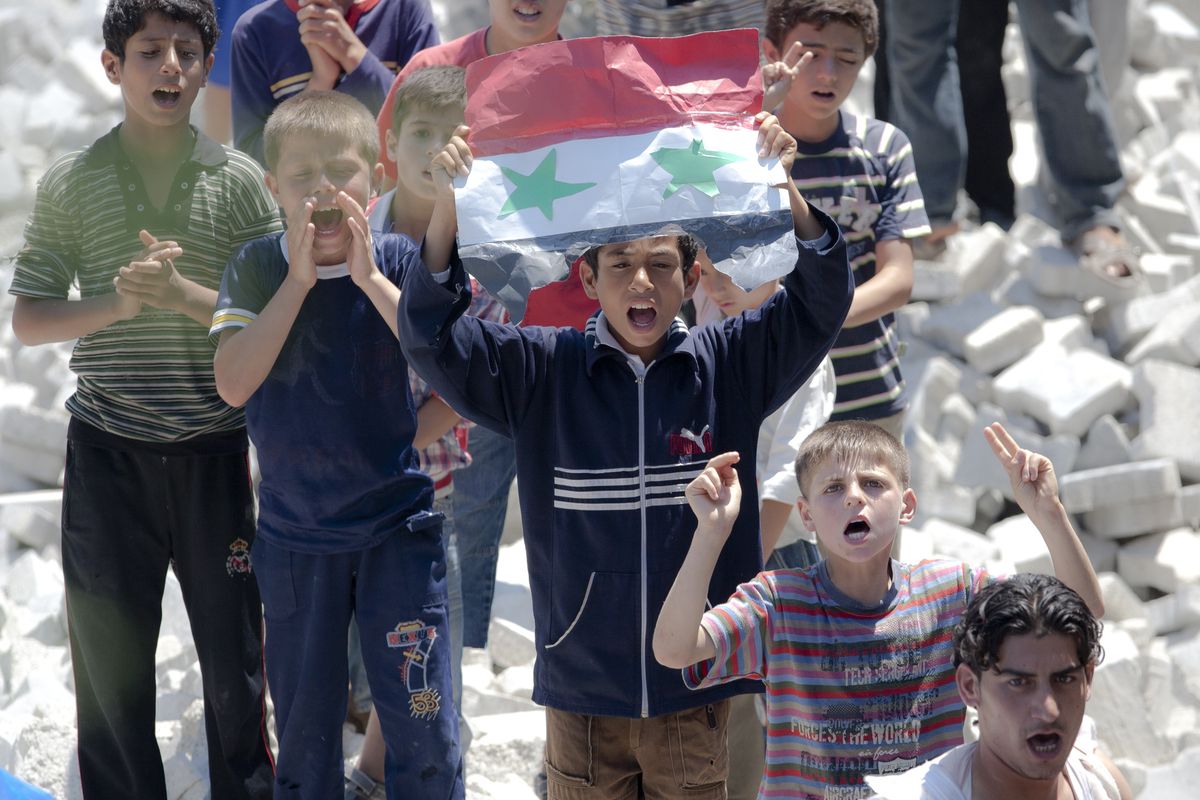 Syrian children hold a handmade Syrian flag during a protest against Syrian President Bashar Assad in a refugee camp in Turkey on Monday. (Associated Press)