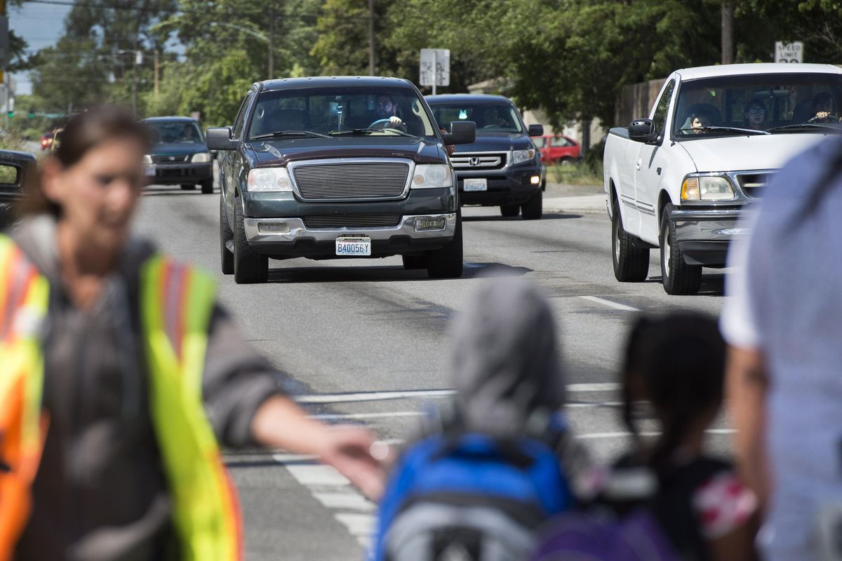 Longfellow Elementary School crossing guard LaCrisha Loper cautions students before assisting them across Nevada at Empire, on Tuesday, June 14, 2016, in Spokane. The school zone speed camera program has issued 4,248 tickets in the Nevada zone since Jan. 1. (Dan Pelle / The Spokesman-Review)