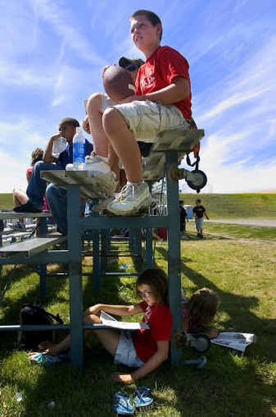 
While Aaron Anderson, 10, watches the Seattle Seahawks practice, Roni Peck, 10, finds a little shade under the bleachers to read the training camp roster Monday at EWU. 
 (Colin Mulvany / The Spokesman-Review)
