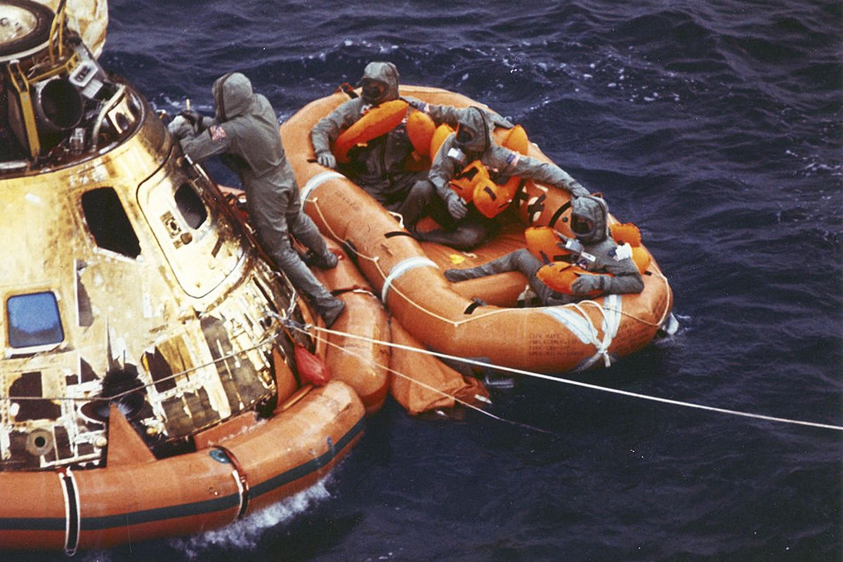 U.S. Navy Lt. Clancy Hatleberg closes the Apollo 11 spacecraft hatch as astronauts Neil Armstrong, Michael Collins, and Buzz Aldrin, Jr., await helicopter pickup from their life raft after splashdown in the Pacific Ocean, on July 24, 1969. (Milt Putnam / U.S. Navy via Associated Press)