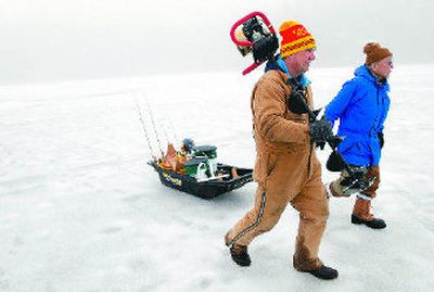 
Fishing buddies Les Florey, left, and Roy Toyama move across Fernan Lake to another fishing spot on Saturday. As ice fishermen, the two are well-equipped with a power augur, a sled designed to hold their gear and warm clothes. 
 (Photos by JESSE TINSLEY / The Spokesman-Review)