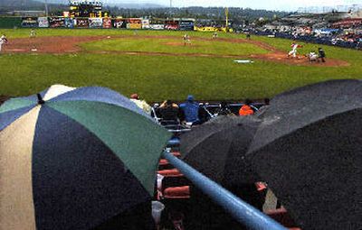 
A little wet but still having fun, the fans of Spokane Indians baseball stay dry under umbrellas Monday night. At the plate John Mayberry Jr. of the Indians bats in the third inning, reaching first base. 
 (Christopher Anderson/ / The Spokesman-Review)