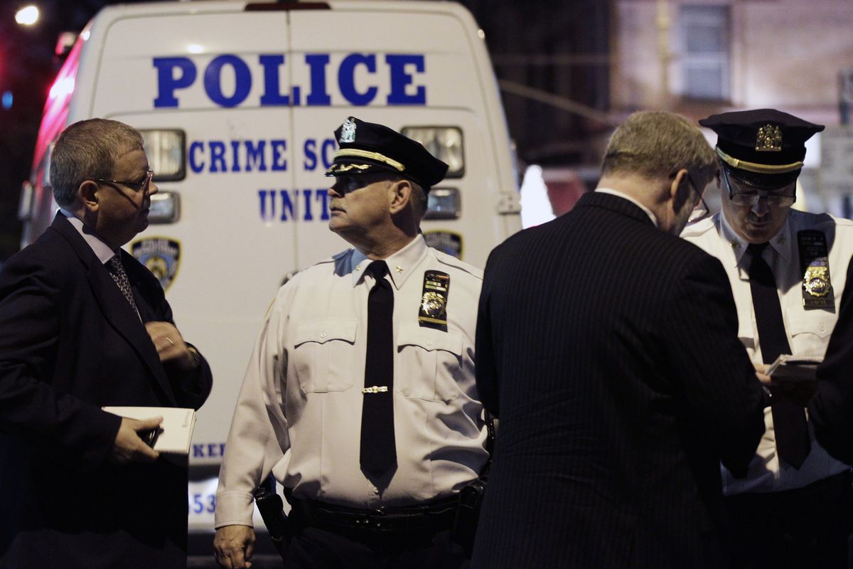 Police confer behind a crime scene unit vehicle in front of the luxury Manhattan apartment building where police say a nanny stabbed two small children to death in a bathtub and then stabbed herself in New York, Thursday, Oct. 25, 2012. Police say the children
