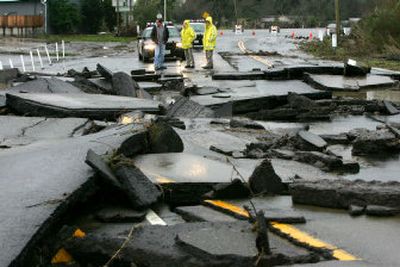 
Daniel Dallara, left, and two California Highway Patrol officers look over the damage on Highway 12 on Sunday in Sonoma County, Calif. A storm Saturday sent rivers rising into cities and mud sliding into homes and across highways. 
 (Associated Press photos / The Spokesman-Review)