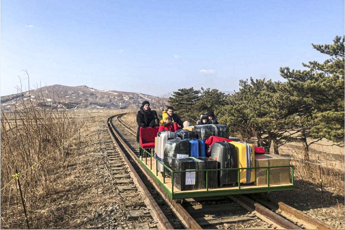 In this image taken from a video released by Russian Foreign Ministry Press Service Thursday, Feb. 25, 2021, a group of Russian diplomats push hand-pushed rail trolley with their children and suitcases to the border with Russia. A group of Russian diplomats and their family members returned to Russia from North Korea on a hand-pushed rail trolley on Thursday because of COVID-19 restrictions in the country, Russia