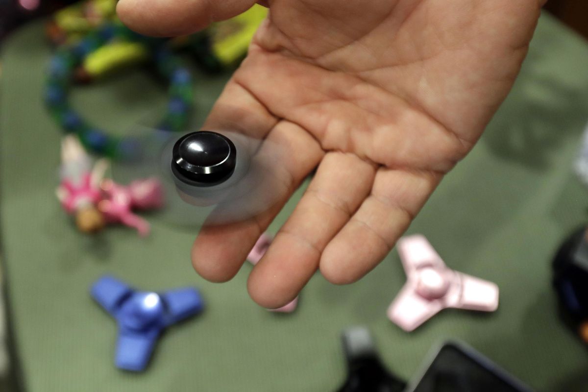 Funky Monkey Toys store owner Tom Jones plays with a fidget spinner in Oxford, Mich. The mania for fidget spinners, the 3-inch twirling gadgets taking over classrooms and cubicles, is unlike many other toy crazes. They