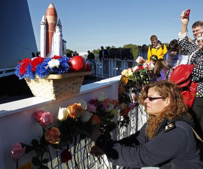 Christine Rooth, lower right,  places a flower in front of the Space Mirror Memorial at a remembrance ceremony to mark the 25th Anniversary of space shuttle Challenger at the Kennedy Space Center visitor complex in Cape Canaveral, Fla., Friday, Jan. 28, 2011. (John Raoux / Associated Press)