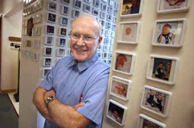 Dr. Alfred Derby stands in the hallway of his office surrounded by hundreds of photos of babies he's delivered during his nearly 40 years of practice in Spokane.
 (Christopher Anderson/ / The Spokesman-Review)