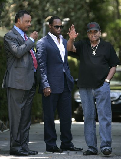 Joe Jackson, right, father of the late pop star Michael Jackson, waves to supporters as the Rev. Jesse Jackson, left, and his son Yusef Jackson look on at the Jackson family home in Encino, Calif., on Friday.  (Associated Press / The Spokesman-Review)