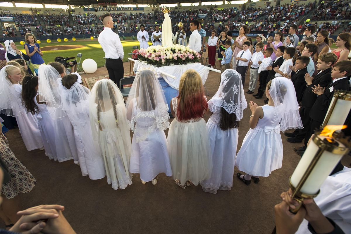 After the procession and crowning of Our Lady of Fatima, first communicants from the Catholic Diocese of Spokane, listen to the song “Ave Maria” at the Eucharistic Family Rosary Crusade held Sunday, July 23, 2017, at Avista Stadium. The event was a joint venture of the Diocese of Spokane and the Society of Our Lady of the Most Holy Trinity. (Colin Mulvany / The Spokesman-Review)