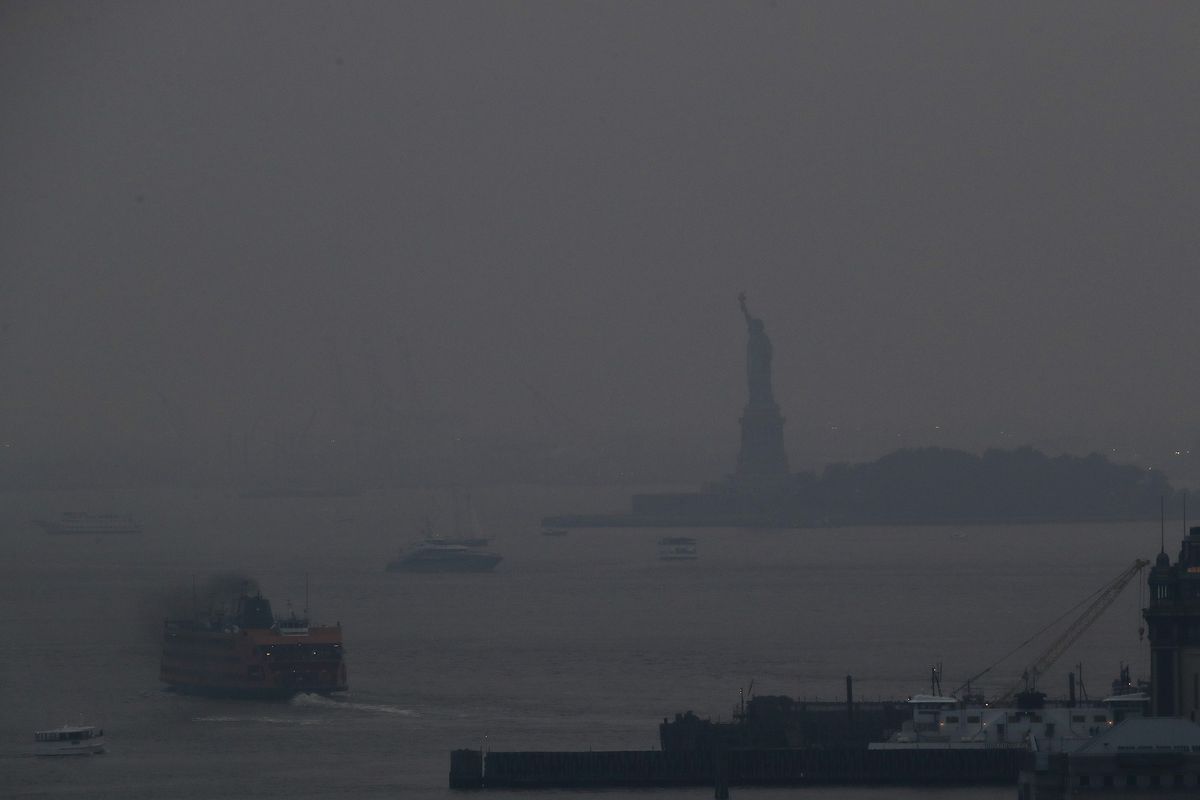 FILE - In this Tuesday, July 20, 2021 file photok the Staten Island Ferry departs from the Manhattan terminal through a haze of smoke with the Statue of Liberty barely visible in New York. Wildfires in the American West, including one burning in Oregon that's currently the largest in the U.S., are creating hazy skies as far away as New York as the massive infernos spew smoke and ash into the air in columns up to six miles high.  (Julie Jacobson)