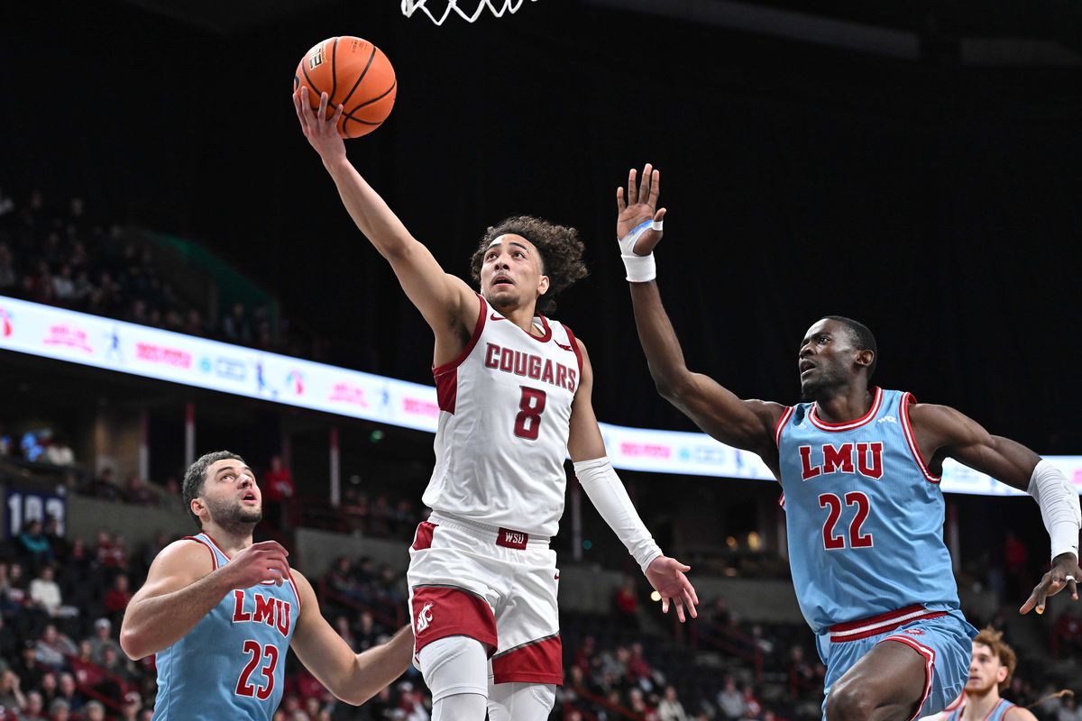 Washington State Cougars guard Nate Calmese (8) makes a basket against Loyola Marymount Lions forward Alex Merkviladze (23) and Loyola Marymount Lions center Rick Issanza (22) in the first half on Mon. Dec. 30, 2024 at Spokane Veterans Memorial Arena in Spokane WA.  (James Snook/For The Spokesman-Review)