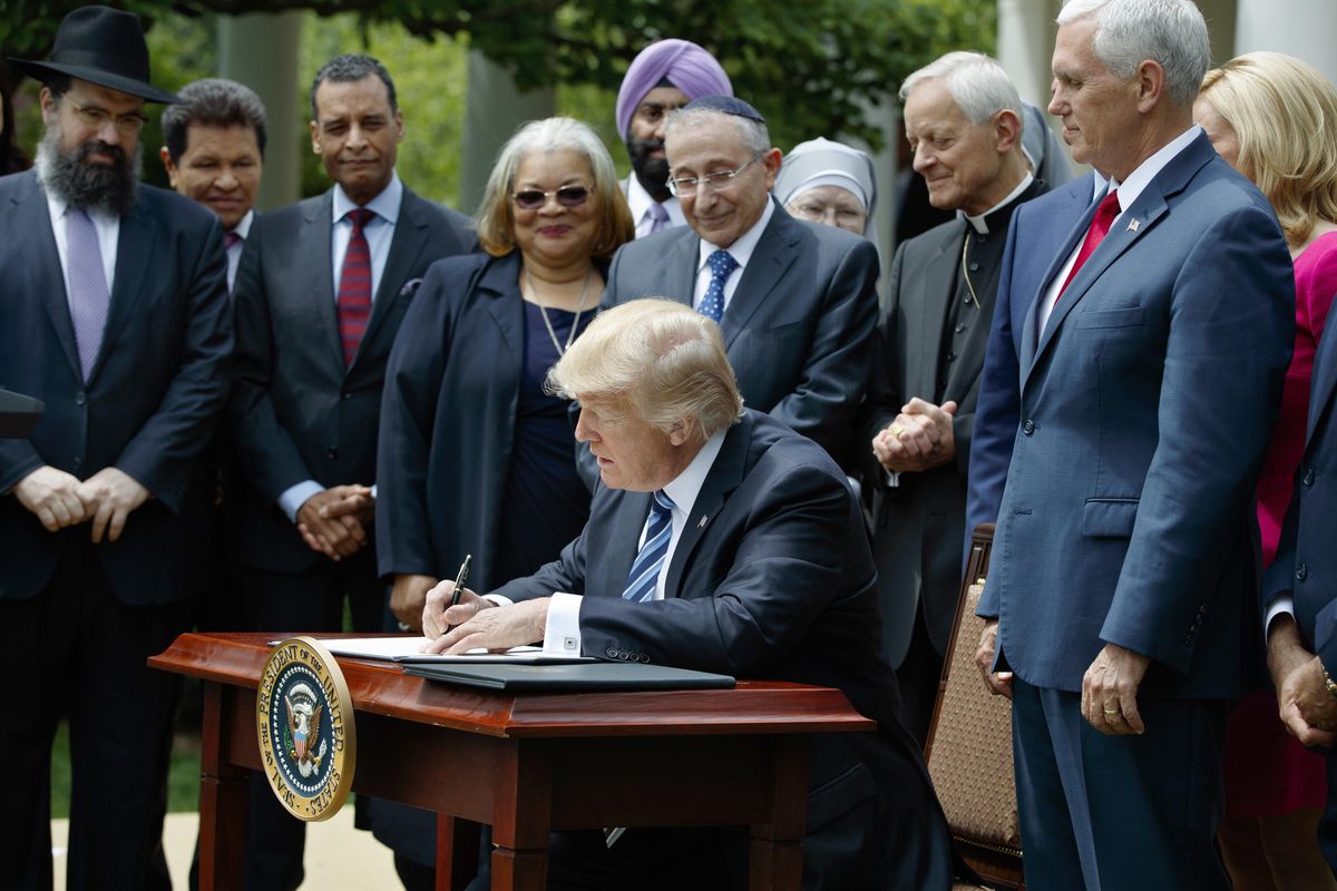 President Donald Trump signs an executive order Thursday aimed at easing an IRS rule limiting political activity for religious organizations, in the Rose Garden of the White House in Washington. The order is drawing a mix of enthusiasm and dread from religious leaders, with some rejoicing in the freedom to preach their views and others fearing it will lead to awkward situations and erode the integrity of the church. (Evan Vucci / Associated Press)