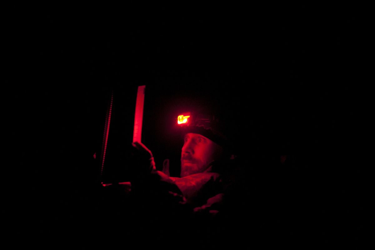 To avoid compromising his night vision, Patrick Graham with Defenders of Wildlife uses a red LED on his headlamp to check a map while bivouacked on a ridge near Adrian Alvarado Baldeon’s herd of sheep on Sept. 10 near Sun Valley, Idaho. Graham spends many nights near sheep herds, employing nonviolent means such as air horns, searchlights and fladry to deter the Pioneer Pack from attacking. (Tyler Tjomsland)