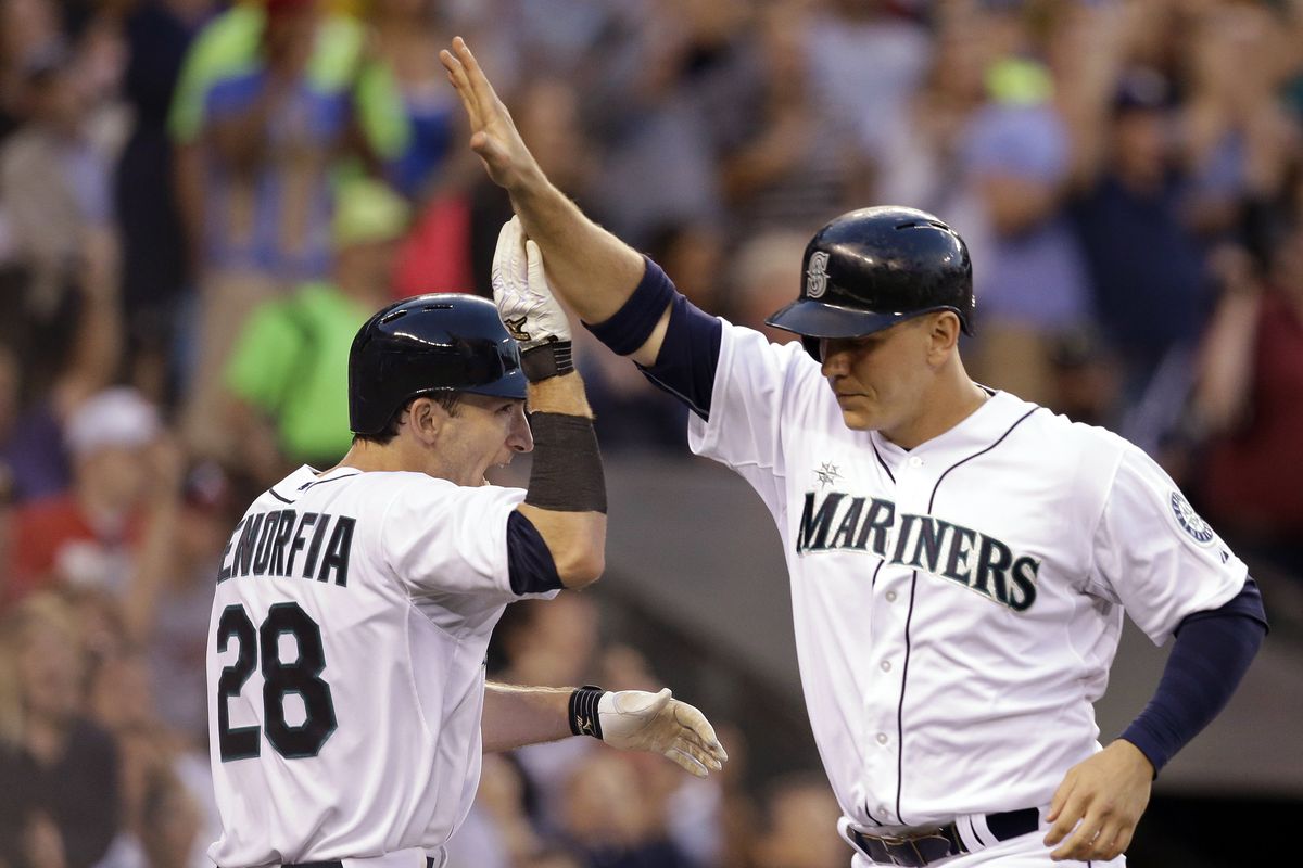 Seattle Mariners’ Chris Denorfia (28) greets Logan Morrison at home as both score on Atlanta second baseman Tommy La Stella’s error. (Associated Press)